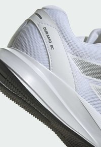 Baskets blanches avec tige en mesh, accents texturés et semelle en caoutchouc. Présente le nom du modèle "Duramo RC" au niveau du talon et un design épuré.