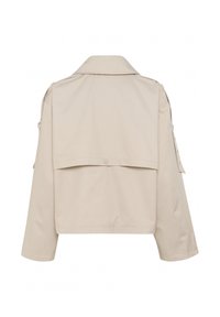 Beige kappa med en strukturerad krage, ryggklaff och två sidofickor. Har långa ärmar och en mjuk, lätt tygtextur.