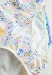 Gros plan sur des gribouillis colorés sur un tissu blanc, comprenant des soleils, des étoiles, des cornets de glace, des signes de paix et des mots comme "Manifesting" et "Hi."