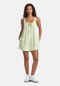 Ljusgrön blommönstrad rompers med fyrkantig halsringning, snörningsdetalj och fickor. Matchad med vita sandaler och en volangankel.
