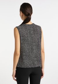 Top fără mâneci, alb-negru, cu un model stropit. Fabricat dintr-un material ușor, având un decolteu rotund și o croială lejera.