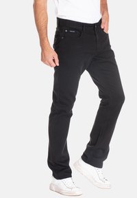 Jeans noirs en denim, avec une coupe droite, un design classique à cinq poches, des passants de ceinture et une étiquette de marque discrète sur la ceinture.