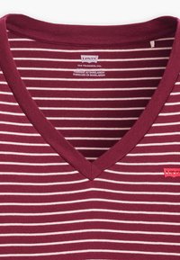 Maroon V-neck t-shirt featuring thin white stripes, soft cotton material, and a red Levi's logo tag on the lower left side.
