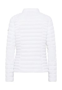 Vit pufferjacka med ribbat mönster, med ståkrage och vadderad design. Ellenbågarna ger extra detalj och struktur.