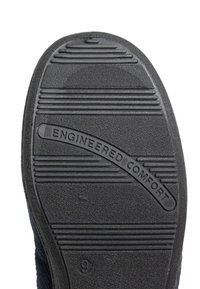 Sole di scarpa in gomma nera con superficie testurizzata, caratterizzata da scanalature orizzontali e la frase "COMFORT INGEGNATO" impressa al centro.