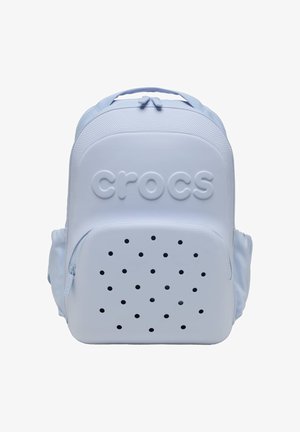 Hellblauer Crocs-Rucksack mit frontaler Reißverschlusstasche, die Belüftungslöcher aufweist, und geprägtem Markennamen am Hauptfach.