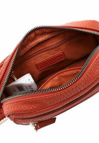 Red leather bag with a textured surface, featuring a zippered interior, an additional pocket, and a fabric lining. Gold hardware accents.