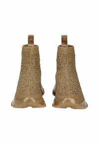 Botines de punto en color beige con una superficie texturizada, adornados con detalles decorativos. Suela de goma y tiras en la parte trasera para facilitar su puesta.