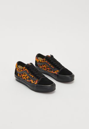 Par de zapatillas bajas con punteras y suelas negras, con laterales estampados de leopardo en naranja y negro y cordones negros.