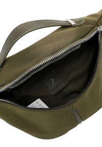 Bolso de tela verde oliva con un acento de cremallera plateada, con un interior texturizado y un asa plana. El interior incluye una etiqueta con el logo.
