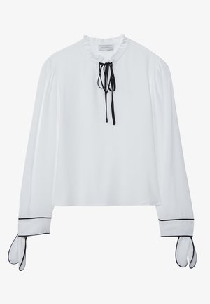 White blouse with a ruffled neckline, black tie detail, and long sleeves featuring black accents at the cuffs. Smooth fabric, relaxed fit.