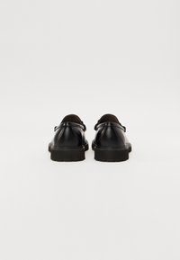 Chaussures en cuir noir avec un bout arrondi, dotées d'une semelle en caoutchouc épaisse et d'une doublure douce marron. Design minimaliste sans métal apparent.