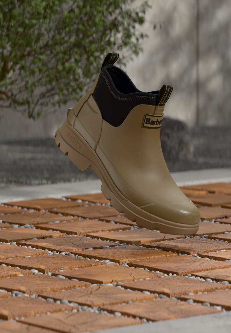 Barbour rubber enkellaars in olijfgroen met een zwarte neopreen manchetten, voorzien van een gestructureerde zool, logo-accenten en een gladde afwerking.