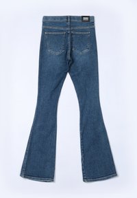 Jeans de mezclilla azul acampanados con cintura alta, que cuentan con dos bolsillos traseros, una textura suave y un detalle de costura mínimo.