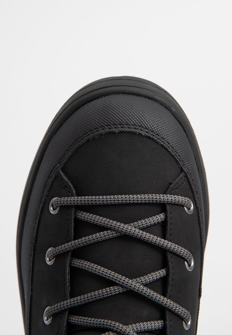 Zwarte schoenen met een gestructureerde bovenkant, ronde neus en grijze veters. Voorzien van metalen oogjes en een rubberen zool voor duurzaamheid.