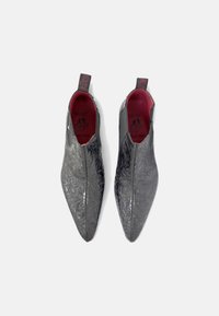 Zapatos de cuero gris con diseño de punta afilada, que presentan una textura floral y un forro interior rojo. Incluyen una lengüeta en el talón.