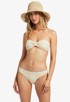 Set bikini in motivo a scacchi pastello con top a bandeau caratterizzato da un nodo frontale e slip a vita bassa; modella che indossa un cappello di paglia.