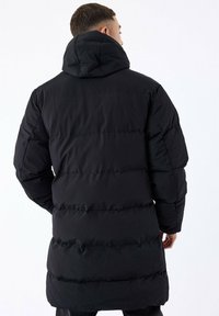 Sort polstret jakke med hætte, med vandret syninger, lange ærmer og en afslappet pasform, designet til varme og komfort.