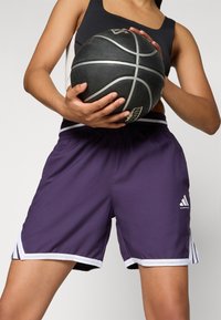 Pantaloni sportivi viola con dettagli e righe bianche, realizzati in tessuto leggero. Adatti per il basket, dotati di un elastico in vita.