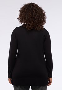 Černý svetr s dlouhým rukávem, ribbovaným lemem, texturovaným materiálem a volným střihem, zobrazený zezadu.
