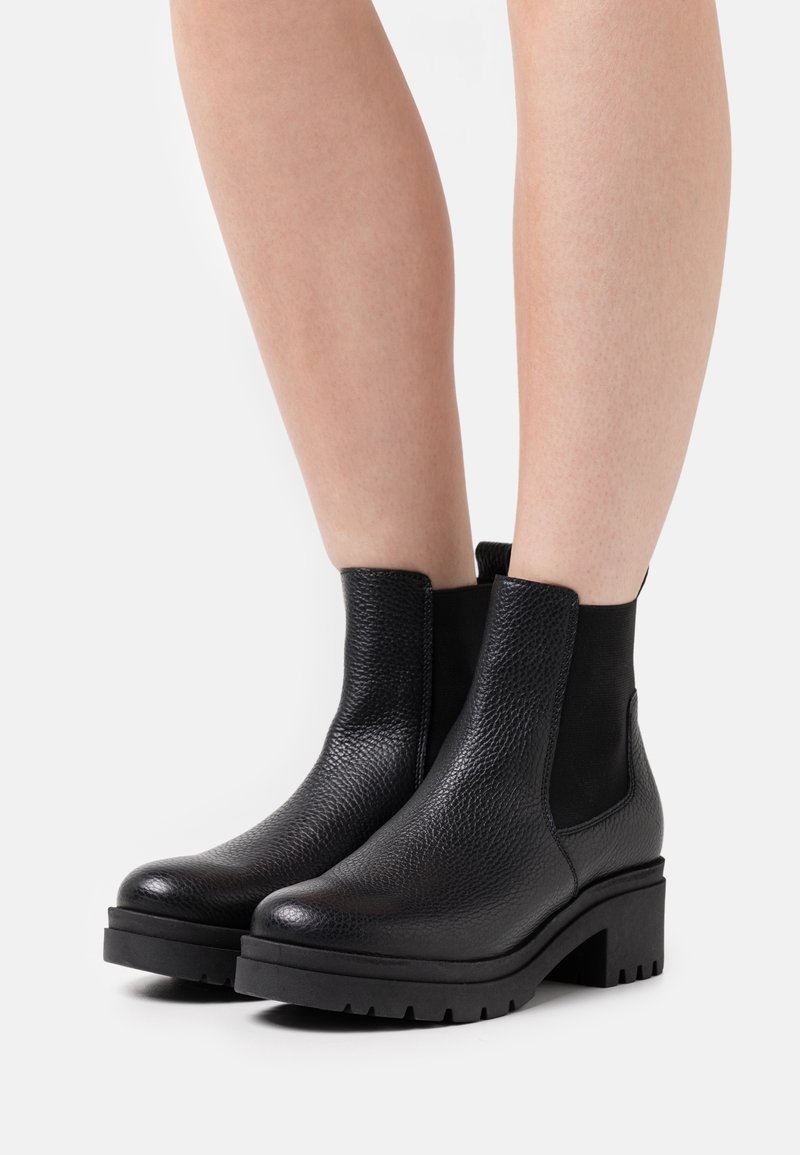 Bottines noires avec une tige en cuir texturé, des panneaux latéraux élastiques et une semelle épaisse et crantée. Design à bout rond.