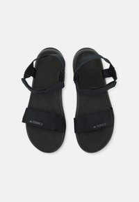 Black sandal with an adjustable strap design, featuring a smooth matte sole and fabric straps, embossed logo on the footbed.