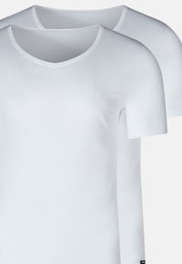 To ensfarvede hvide kortærmede bomulds t-shirts med rund hals, der overlapper på en lys grå baggrund.