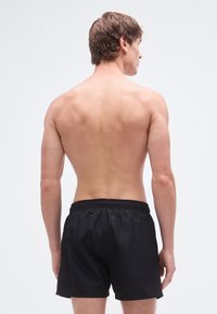 Juodi maudymosi šortai su elastinga juosmens juosta, pagaminti iš lygios, lengvos medžiagos. Pavaizduota prekės nugarinė pusė.