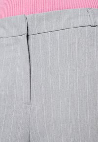 Szara tkanina w prążki o gładkiej fakturze, z dopasowanym pasem i równoległymi jaśniejszymi liniami, nadającymi uporządkowany wygląd.