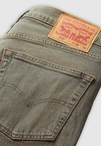 Poche arrière et étiquette en cuir Levi Strauss & Co. sur un jean en denim bleu délavé, taille W32 L32, modèle 515.