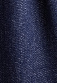 Vue en gros plan d'un tissu en denim bleu foncé montrant la texture et le motif de tissage.