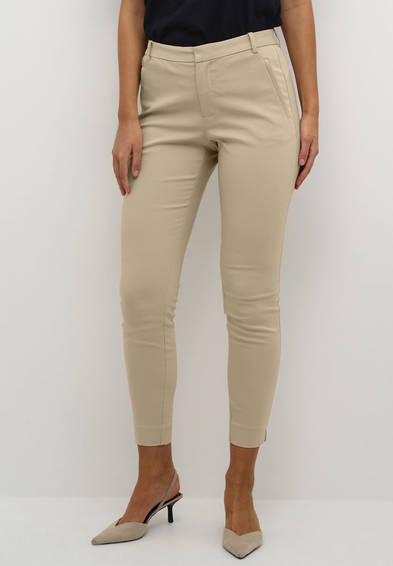 Pantaloni beige su misura con una vestibilità slim, dotati di tasche laterali, una vita senza cuciture e una finitura in tessuto elasticizzato e liscio.