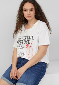 Witte katoenen T-shirt met een graphic print van een drankje met een rietje en tekst. Gecombineerd met denim shorts, wat een casual stijl uitstraalt.