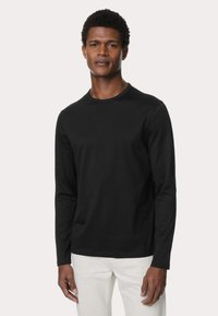 Camiseta negra de manga larga en corte ajustado con cuello redondo, hecha de algodón, con una textura suave y sin patrones ni acentos visibles.