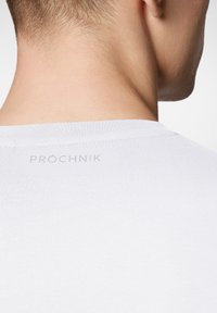 Biała bawełniana koszulka z okrągłym dekoltem i gładką teksturą. Logo "PRÓCHNIK" subtelnie nadrukowane na tylnym dekolcie.