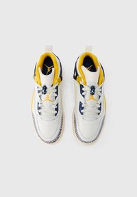 Λευκά και ναυτικά αθλητικά παπούτσια με κίτρινα στοιχεία, υφή από δέρμα, σχέδιο με κορδόνια και πατούμενα από καουτσούκ με σχέδιο. Διαθέτουν λογότυπο στην κορυφή.