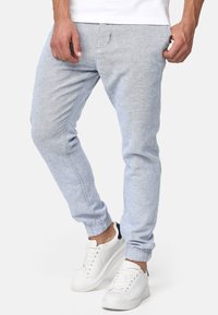 Pantalones jogger de color azul claro hechos de una tela texturada, con una cintura elástica y puños. Combinados con zapatillas blancas.