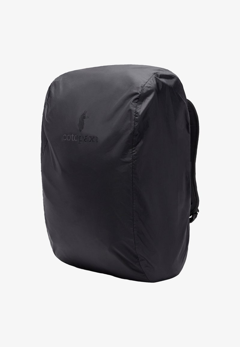 Mochila negra hecha de un tejido ligero y brillante. Presenta bordes redondeados y un logo sutil en la parte frontal. Cintas ajustables en los laterales.