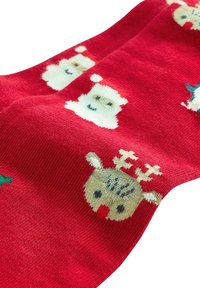 Røde sokker med festlige mønstre af julemanden og en rensdyr. Blød tekstur med grønne accenter og kontrasterende designs gennem hele sokken.