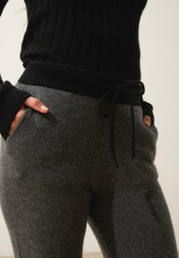 Svart ribbad tröja i kombination med mörkgrå fleece-joggingbyxor med dragsko i midjan, sidofickor och en mjuk, slät textur.