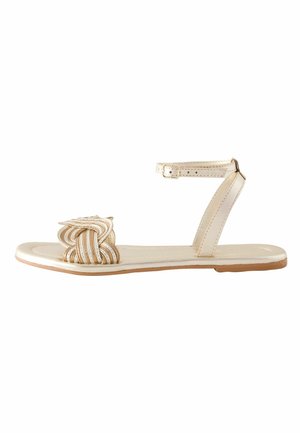 Sandale joasă bej cu bretea pentru gleznă și cataramă, având o bretea frontală împletită decorativ și o talpă subțire.