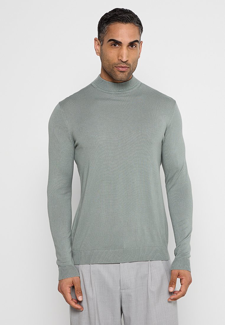 Hellgrüner, gerippter Rollkragenpullover mit langen Ärmeln. Aus weichem Stoff gefertigt, mit einer taillierten Passform und einer glatten Textur.