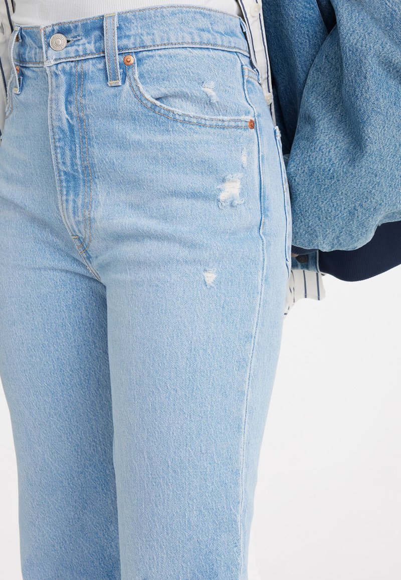 Hellblau, ausgewaschene Jeans im geraden Schnitt, mit sichtbaren Franseneffekten, Fronttaschen und Kupfennieten.