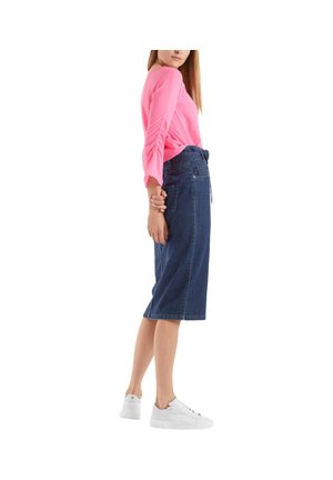 Denim skirt with a straight cut, mid-length, dark wash; paired with a bright pink, long-sleeve top and white sneakers.