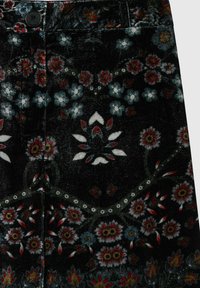 Tissu noir avec des boutons ornés de motifs floraux complexes en rouge, blanc et bleu, disposés de manière symétrique sur la surface.