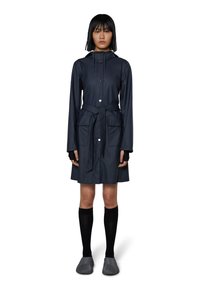 Tummansininen vedenpitävä trench-coat, jossa on huppu, kiristettävä vyötärö ja kaksi etutaskua. Varustettu napituspainikkeilla ja sileällä pinnalla. Yhdistä mustiin sukkiin ja teksturoituihin liukuviin kenkiin.
