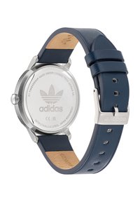 "Adidas" laikrodis su nerūdijančio plieno korpusu, tamsiai mėlyna odine apyranke, sidabro spalvos detalėmis ir tekstūruotu nugarėlė. Korpuse išgraviruotas logotipas.