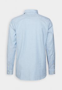 Chemise habillée pour homme à manches longues avec des rayures verticales bleu clair et blanches, vue de dos sur un fond uni.