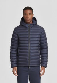 Giacca piumino navy con design trapuntato, chiusura con zip e cappuccio. Presenta tasche laterali e una texture liscia e lucida. Leggera e isolante.