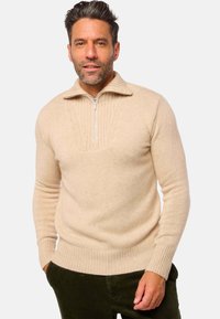 Beige Pullover mit Reißverschluss am Hals, mit gerippten Bündchen und Saum, ausgestattet mit einem strukturierten Muster am Kragen und oberen Brustbereich. Weicher Strickstoff.